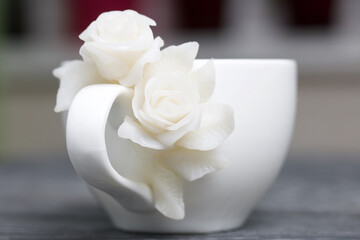 Handmade cup decorated with polymer clay roses. Jewelry made of white polymer clay.