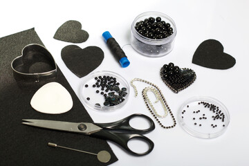Crafts from beads. Materials for making brooches from black felt and beads.