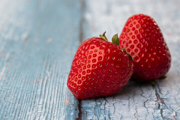 Fresh ripe perfect pieces strawberry on blue wooden background. Fresh strawberry as texture background. Natural food backdrop with red berries. Strawberries sale in a food market in summer.