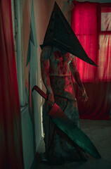 Cosplayer in the image of executioner stands in dark room with knife