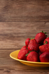 Fresh strawberries in plate on wooden table. Fresh nice strawberries. Strawberry field on fruit farm. Heap of Red strewberry on plate close up. Juice strawberry. Strawberry field on fruit farm.