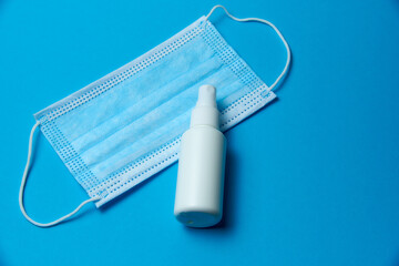 Medical mask with a disinfectant bottle on a blue background