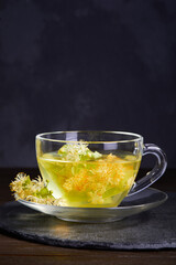 Transparent glass cup of tea with linden on a dark background. Copy space
