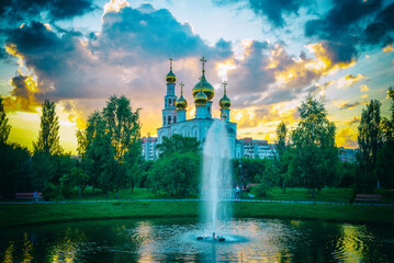 Fototapeta premium Golden domes of the Russian Orthodox Church. Transfiguration Cathedral on the background of the fountain in the city park. Russia. Abakan