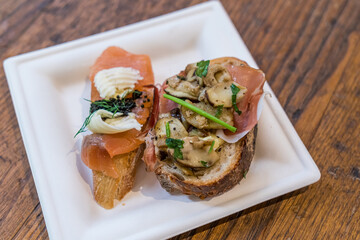 Assortment of Italian bruschettas with smoked salmon and caviar and smoked ham and mushroom.