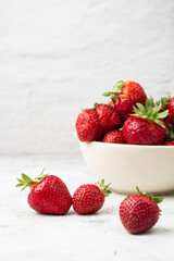 Fresh strawberries in a bowl on marble white table. Fresh nice strawberries. Strawberry field on fruit farm. Heap of Red strewberry on plate close up. Juice strawberry. Strawberry field on fruit farm.