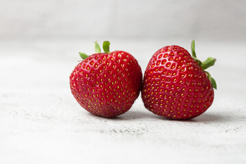Fresh ripe perfect strawberry on white marble background. Two fresh strawberry isolated. Natural food backdrop with red berries. Strawberries sale in a food market in summer.