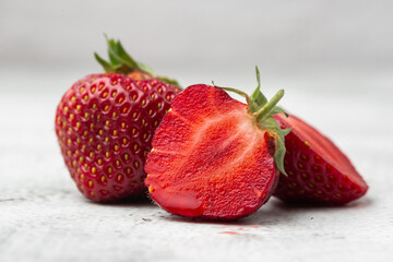 Fresh ripe perfect pieces strawberry on white marble background. Fresh strawberry as texture background. Natural food backdrop with red berries. Strawberries sale in a food market in summer.
