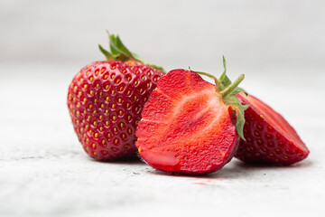 Fresh ripe perfect pieces strawberry on white marble background. Fresh strawberry as texture background. Natural food backdrop with red berries. Strawberries sale in a food market in summer.