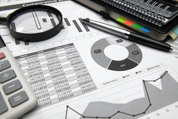 business office desk closeup - financial reports, analysis and accounting, set of documents, tables and graphs, various items for bookkeeping, calculator