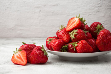 Fresh strawberries in plate on marble white table. Fresh nice strawberries. Strawberry field on fruit farm. Heap of Red strewberry on plate close up. Juice strawberry. Strawberry field on fruit farm.