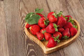 Fresh strawberries in a wooden plate on wooden table. Fresh nice strawberries. Strawberry field on fruit farm. Heap of Red strewberry on plate. Juice strawberry. Strawberry field on fruit farm.