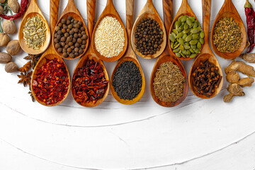 Top view of different spices on white textured background