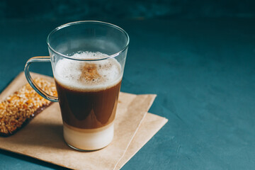 Latte macchiato on a blue background. Coffee layers in a glass mug.