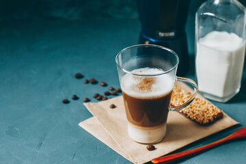 Latte macchiato on a blue background. Coffee layers in a glass mug.