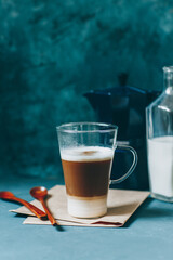 Latte macchiato on a blue background. Coffee layers in a glass mug.