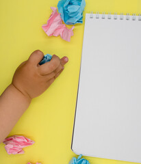 Children's hand on a table with colored paper. Kindergarten, kindergarten, preschool education. Flat lay, copy space, top view.