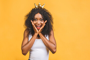 Young african american woman wearing golden crown of queen over isolated over yellow background...