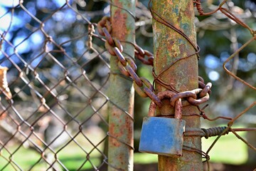 Old rusty lock on an old rusty fence. Rusty lock, chain and fence in the garden.