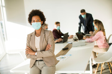 African American woman in office wear mask as protection from corona virus
