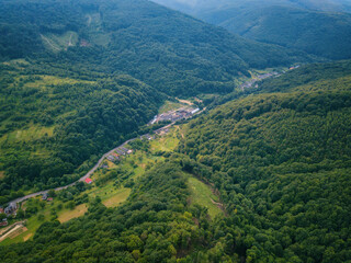 Aerial view of the beautiful wooded Carpathian mountains and small village, summer landscape, outdoor travel background, Transcarpathia (Zakarpattia), Ukraine