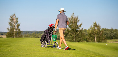 A man changing position on the golf course. Golf player walking with a golf club cart.