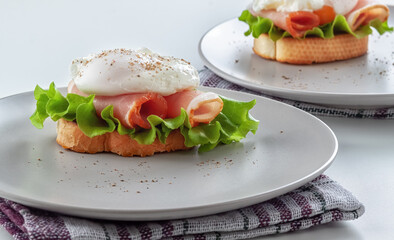 Benedict eggs on a toasted baguette with bacon and salad and on a platter