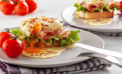 Eggs Benedict on toasted muffins with ham and sauce