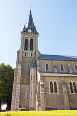 Fototapeta na wymiar Beautiful long shot of Notre-Dame-de-l'Assomption church (La Lande Patry, Normandy, France). Sunny day in the north of France. Stone christian church.