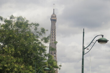 Obraz premium Haut de la tour Eiffel a coté d'un arbre et d'un lampadaire