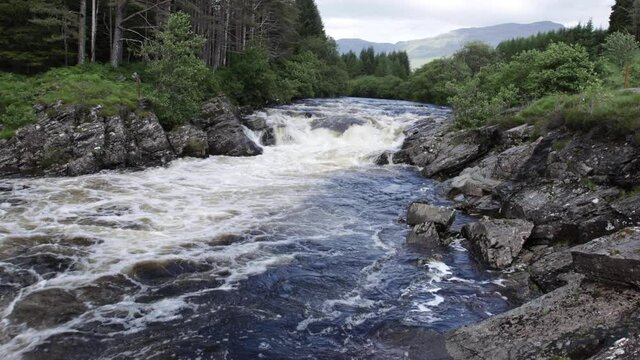 Aerial drone footage of the waterfalls in Glen Orchy near Bridge of Orchy in the Argyll region of the highlands of Scotland during summer whilst the river is flowing fast from rainfall