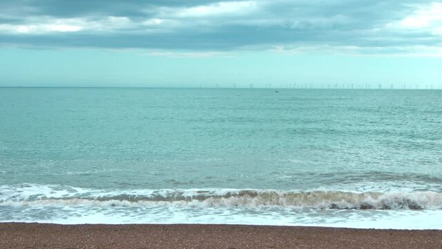 Beach waves in slow motion in Brighton, England. Sea waves on a cloudy and windy day in 4K.
