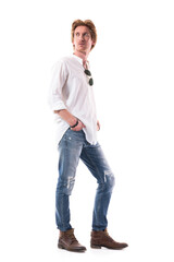 Calm relaxed young casual man in jeans looking back over shoulder with hands in pockets. Full body length isolated on white background. 