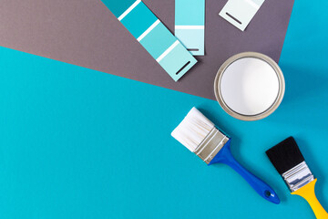 Can of white paint with brushes on colorful background, selection of palette for painting, sample...
