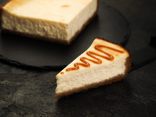 tasty homemade classic cheesecake new york and a slice of watered caramel topping on a dark background