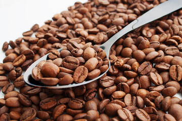 coffee beans in a spoon on coffee beans heap