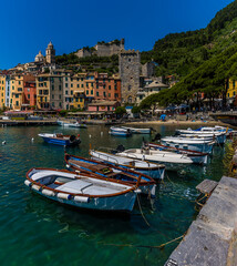Small fishing boats line up along the quay in front of the old town of Porto Venere, Italy in the summertime