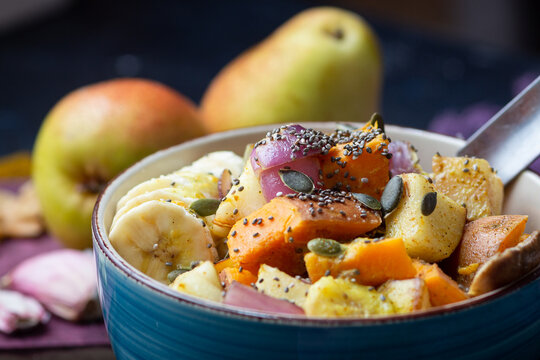 Veganes Curry mit Süßkartoffeln, Birnen, Bananen und Chiasamen in einer blauen Schüssel mit Birnen im Hintergrund