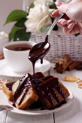 A female cook pours chocolate on a freshly baked cupcake. Homemade cakes, muffins, pie. Self-isolation of the house.