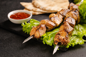 Two portions of shish kebab on a stone plate with salad.