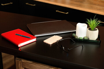 laptop, notepad, phone, glasses and a vase with a plant on a business table