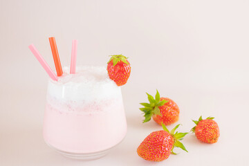 Strawberry milkshake on a light background in a transparent glass. Around - strawberries. The concept of delicious fresh drinks, healthy food for breakfast and snack.