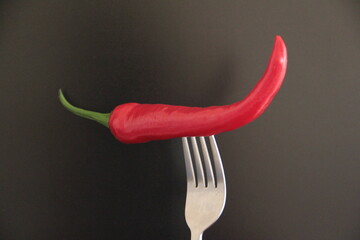 organic red pepper in a fork on a black background