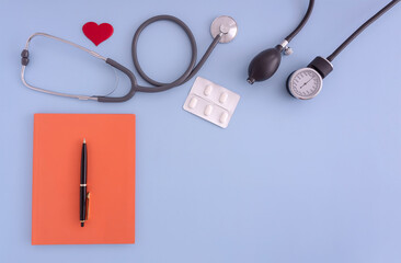 stethoscope, blood pressure monitor, a notebook, pen, tablet on a blue background. concept medicine...
