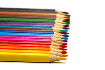 Fototapeta premium colored pencil set loosely arranged on white background, selective focus