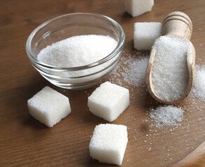 Bowl and scoop with white sand and  sugar cubes on wooden background