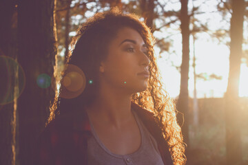 Menina adolescente negra com cabelos cacheados volumosos, ao pôr do sol, em uma floresta. Beleza afro, beleza negra.
Clima de outono