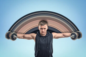 Strong muscular young man in black sportswear holding two dumbbells on blue background