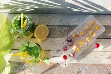 
Cold drink of citruses, cucumbers and mint in glass cups, ice with cherries on a wooden table, detox water, home cooking, healthy food