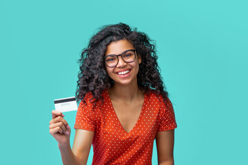 Close up portrait of attractive girl with prfect smile holding credit card in hand over bright blue background